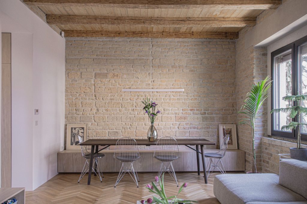 interiér s tehlovou stenou dreveným stolíkom a kovovými barovými stoličkami