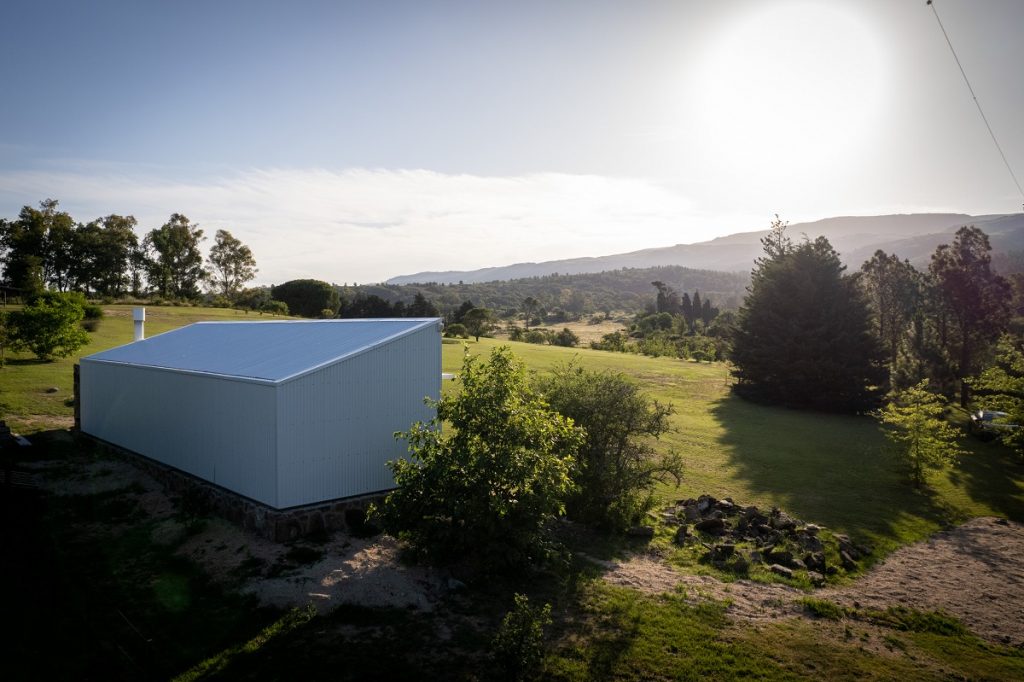 biely modulárny plechový dom v krajine so zeleňou