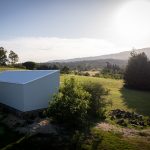 biely modulárny plechový dom v krajine so zeleňou