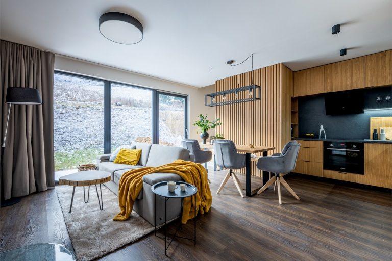 obývačka horskej chaty so sivou sedačkou a stoličkami a so žltou dekou