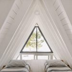 spálňa pod bielym dreveným obkladom štítovej strechy, relaxačná sieť, dve postele