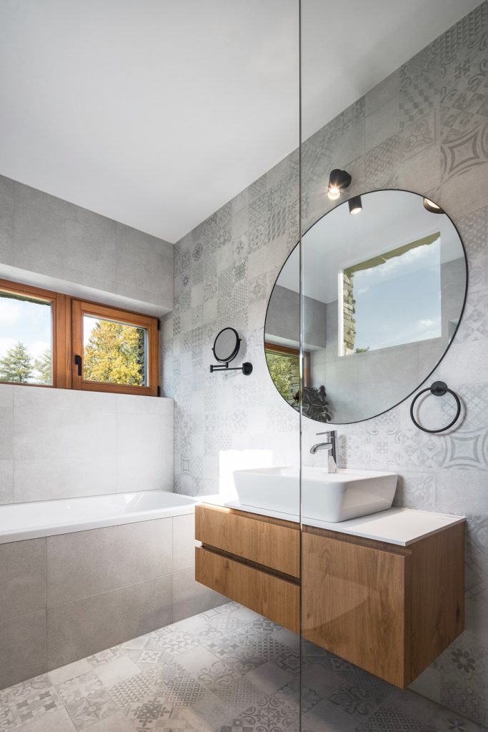 kúpeľňa s okrúhlym zrkadlom a sprchovacím kútom