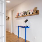 modrý stolík s lampou, nad ktorým je otvorená polica s knihami