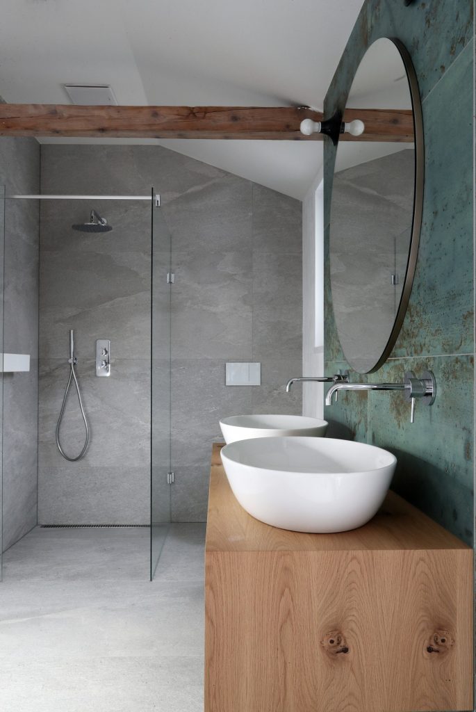 sprchocací kút a zrkadlo v kúpeľni so sivou a zelenou stenou