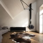 obývačka s oceľovým krbom, sivou sedačkou a kravskou kožou na podlahe