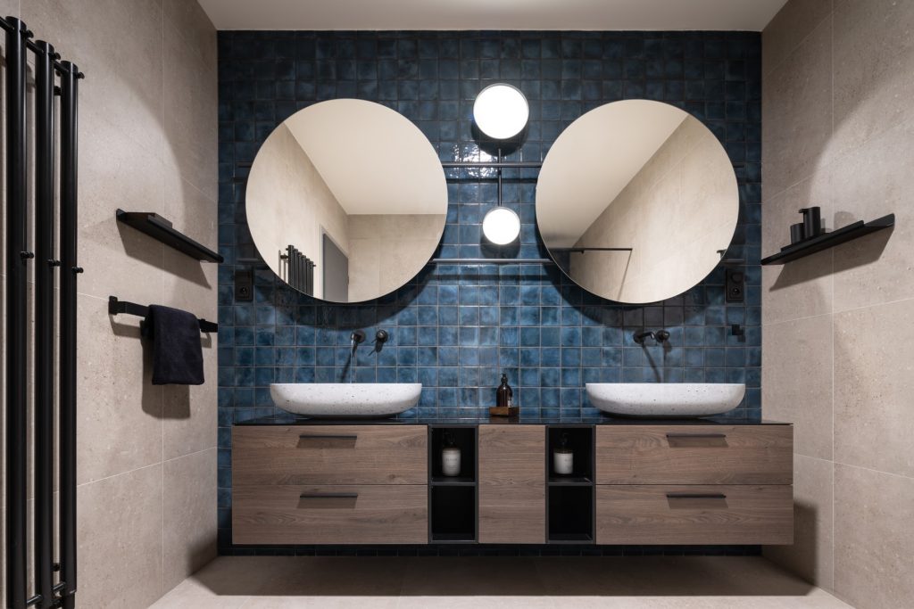 Kúpeľňa s dvomi umývadlami a dvomi zrkadlami na modrej stene