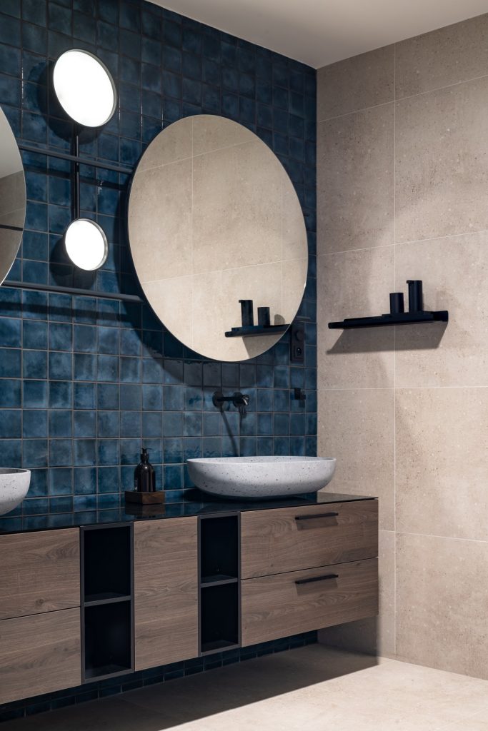 Kúpeľňa s modrým obkladom a zrkadlami za dvomi umývadlami