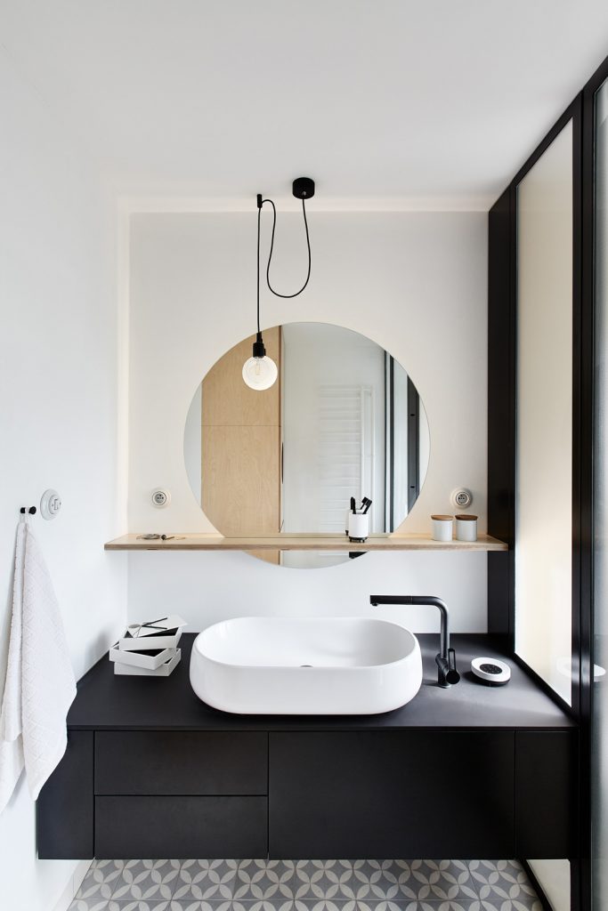 kúpeľňa s umývadlom na čiernej skrinke a so zrkadlom