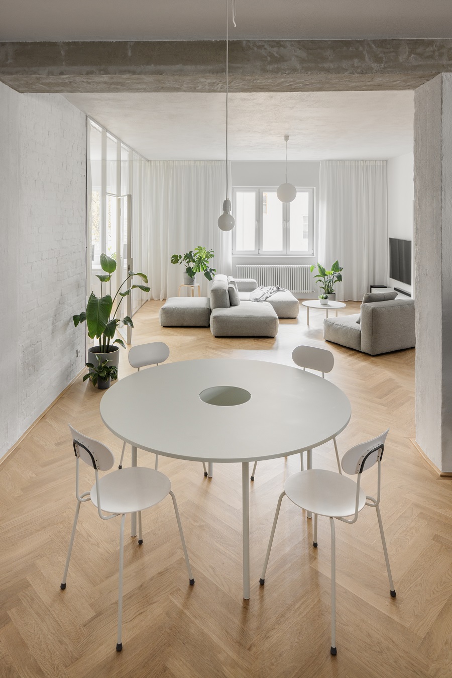 otvorený denný priestor s jedálenským stolom, sivou sedačkou a dubovou podlahou