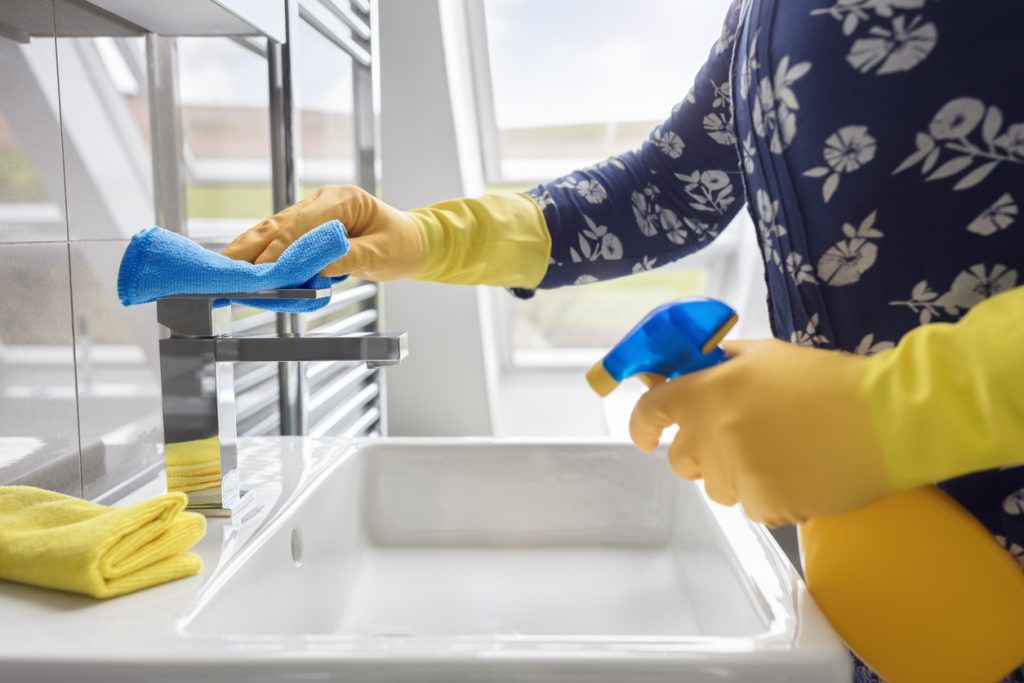 ženská ruka v žltej gumovej rukavici čistí sanitu