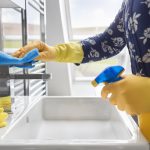 ženská ruka v žltej gumovej rukavici čistí sanitu