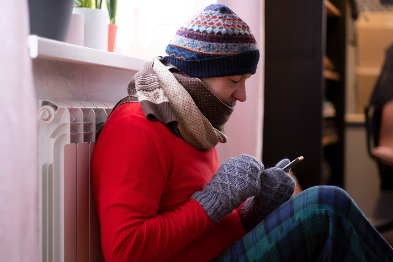 Man feeling cold at home with home heating trouble
