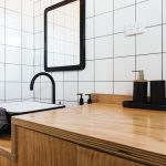 kúpeľňa s dreveným nábytkom a bielymi kachličkami čierna sanita
