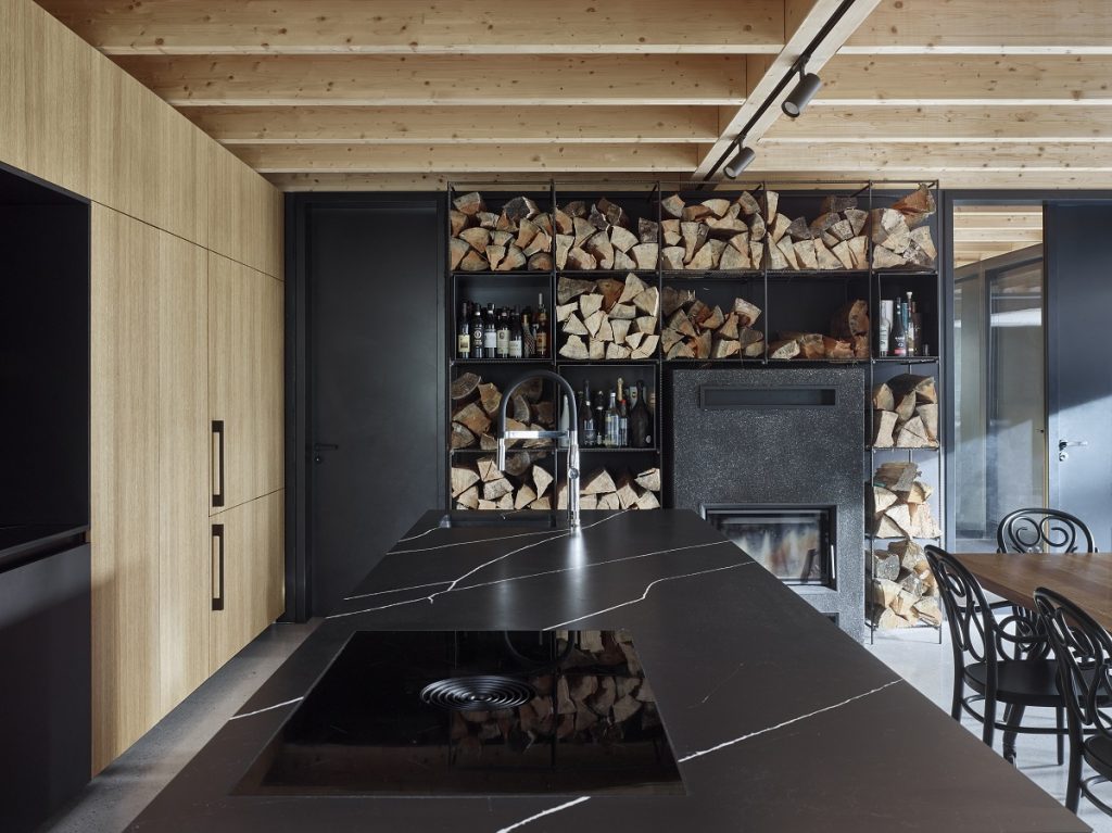 kuchyňa s dreveným stropom, čiernou kuchynskou linkou a policami na ukladanie dreva
