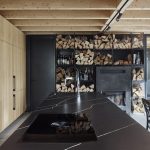 kuchyňa s dreveným stropom, čiernou kuchynskou linkou a policami na ukladanie dreva