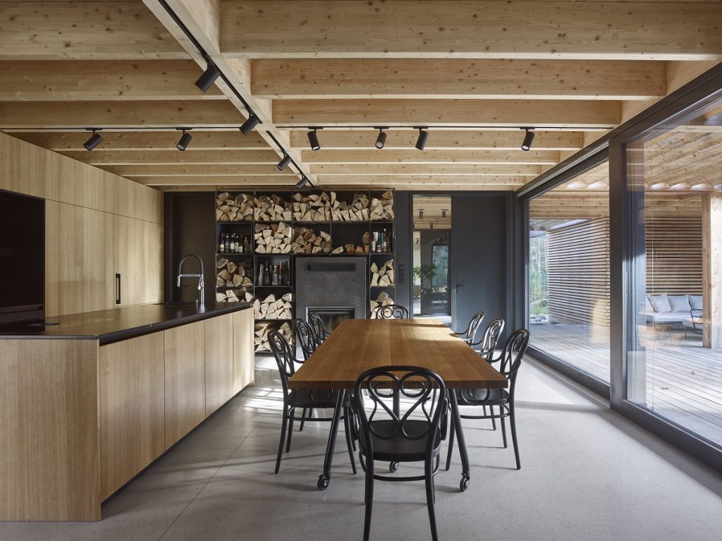 kuchyňa s dreveným stropom, policami na ukladanie dreva, stolom a čiernymi stoličkami
