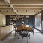 kuchyňa s dreveným stropom, policami na ukladanie dreva, stolom a čiernymi stoličkami