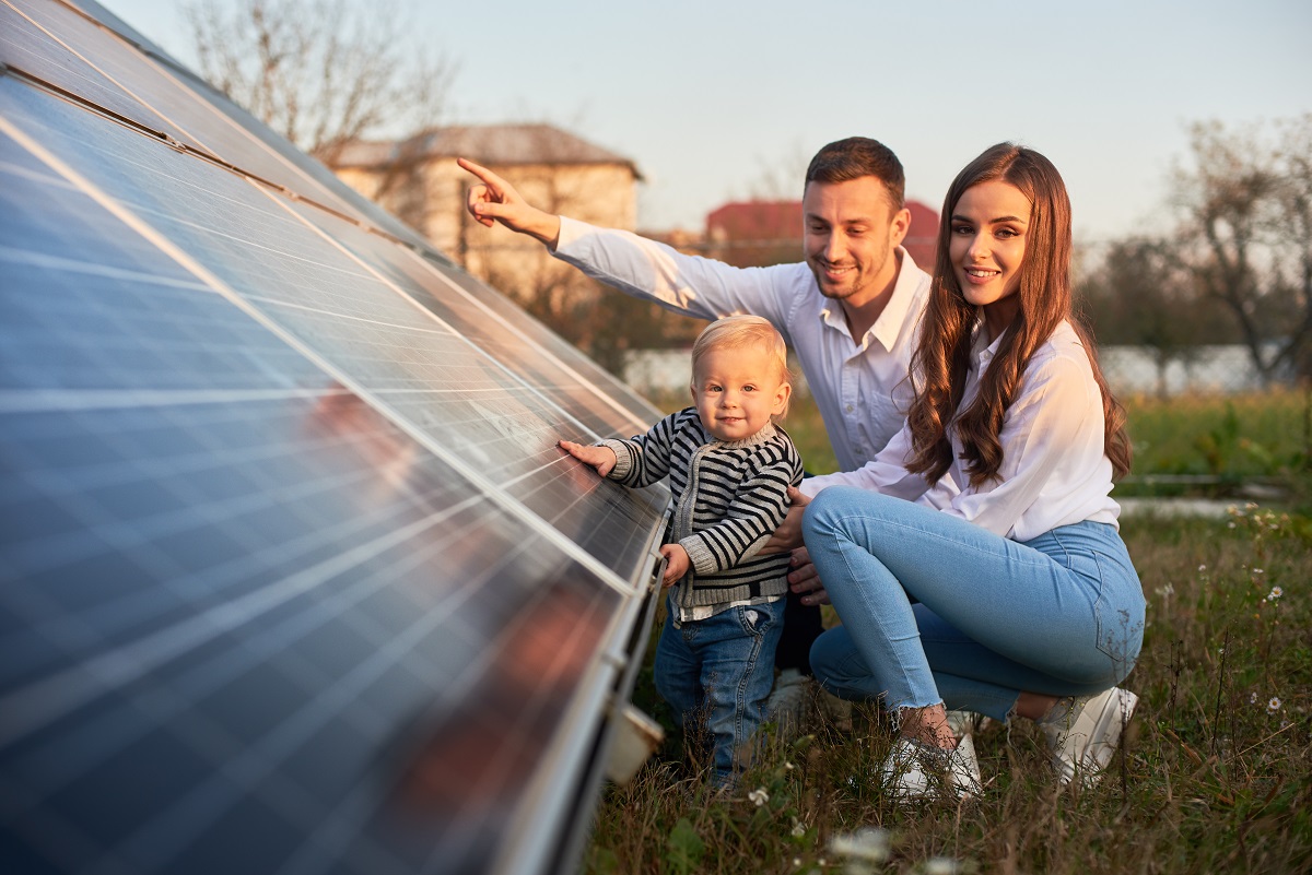 A,Young,Family,Of,Three,Is,Crouching,Near,A,Photovoltaic