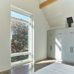 presvetlená spálňa s veľkým oknom a bielymi skriňami