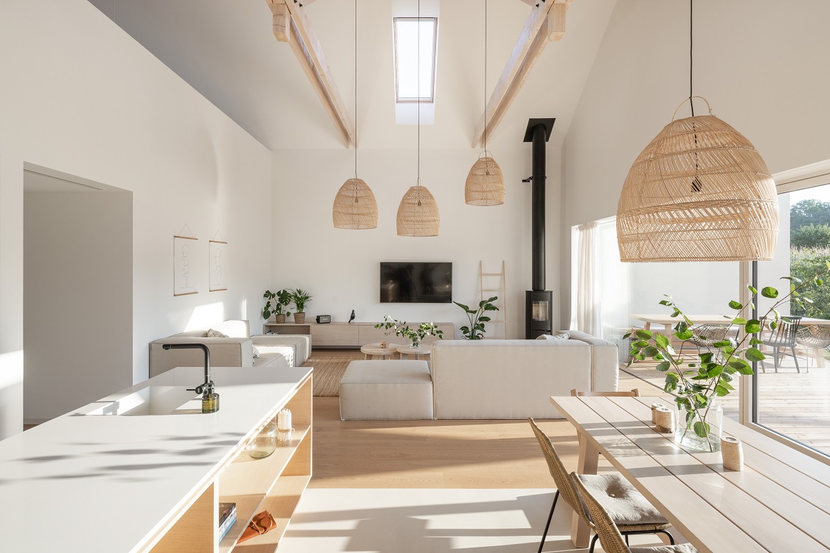 noderná bielo-béžová obývačka s kuchyňou otvorená do krovu, ratanové svietidlá, kuchynský ostrov