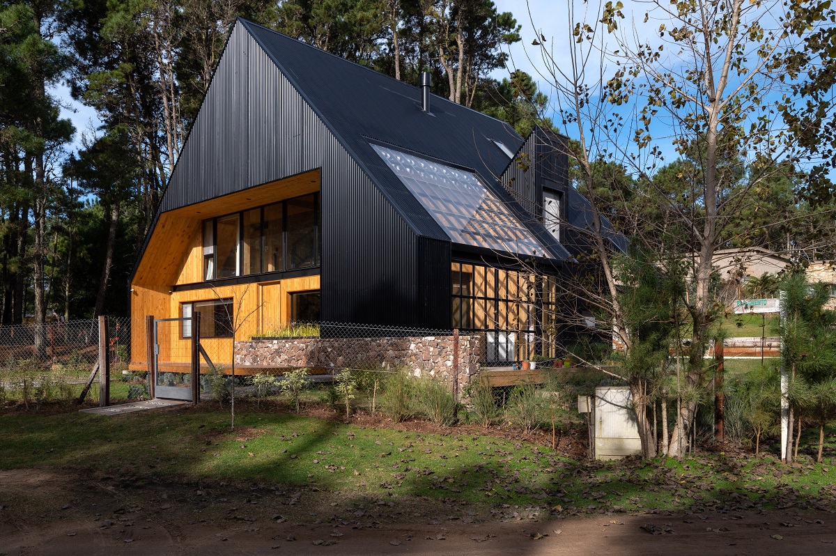 moderný dom v lese s čiernou štítovou strechou