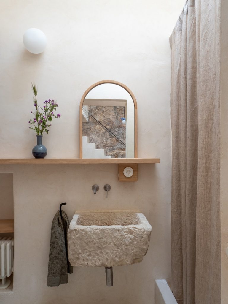 kúpeľňa s okrúhlym zrkadlom a kamenným umývadlom