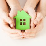 detské a ženské ruky držia zelený dom, udržateľné stavebníctvo symbol