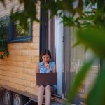 žena s notebookom sedí pred mobilným domom
