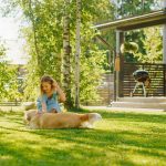 dievčatko so psom na trávniku pri terase