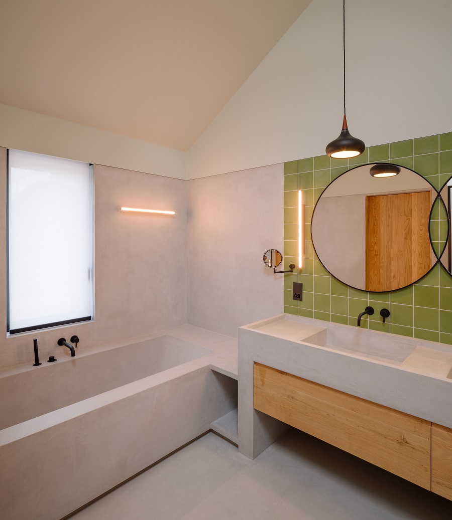 kúpeľňa so zeleným obkladom a okrúhlym zrkadlom