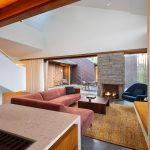 veľká obývačka s krbom, kamenným a dreveným obkladom, červeným gaučom a modrým kreslom