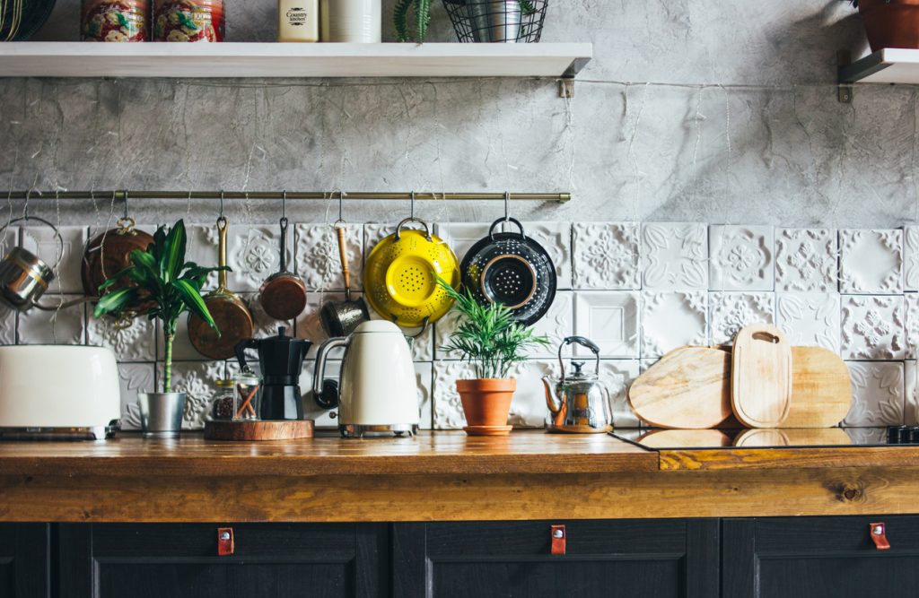 kuchynské náčinie zavesené na stene, cedidlo, doska na krájanie, bylinky, vintage kuchyňa