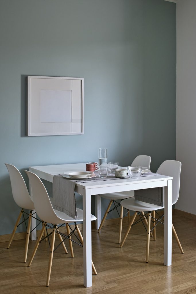 biely stôl a stoličky pri modrej stene