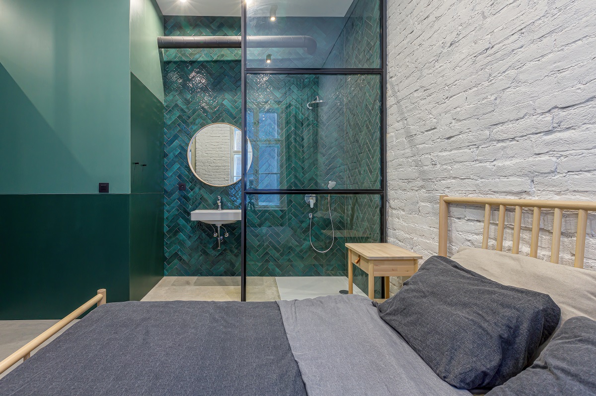 spálňa s tehlovou stenou a tyrkysovo zelenou kúpeľňou
