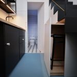 malá kuchynská linka, čierna, svetlé drevo, otvorené dvere na WC, schodisko