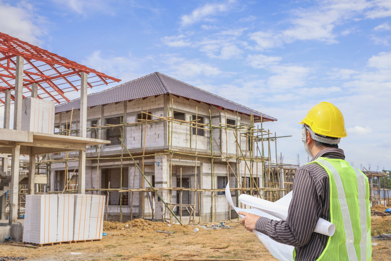 Professional engineer architect worker with protective helmet and blueprints paper at house building construction site