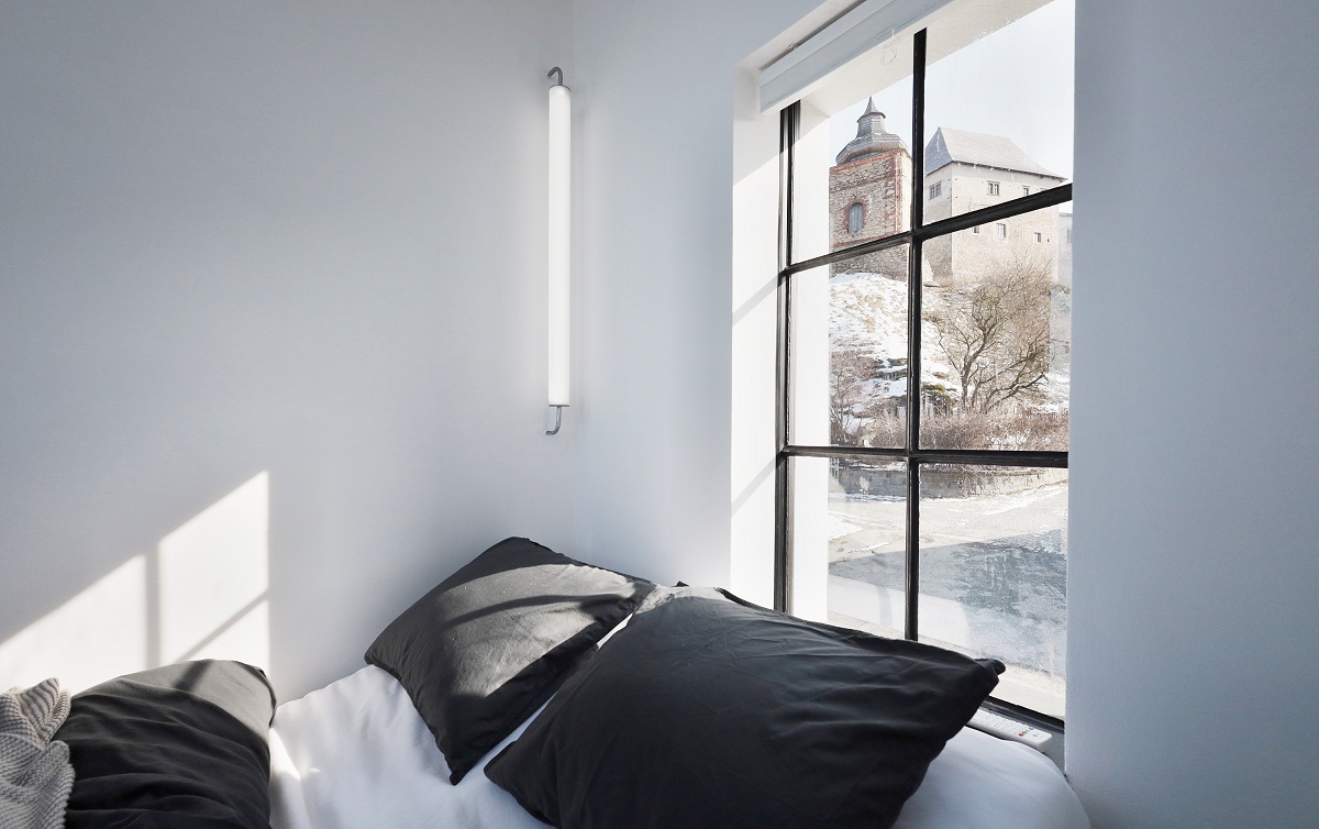 manželská posteľ pri okne, čierne obliečky na vankúšoch