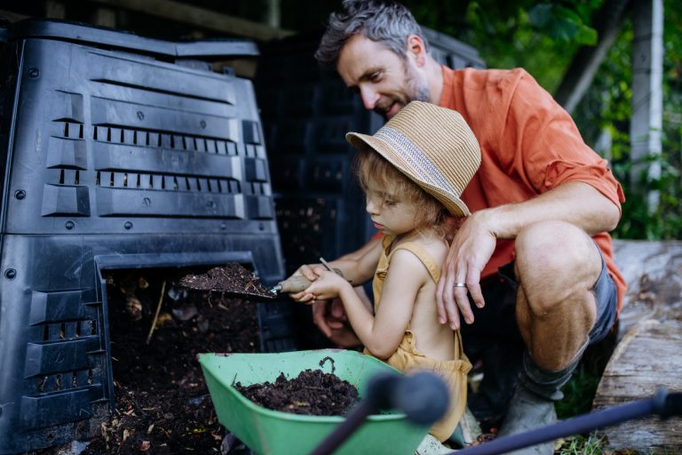 otec a dcéra naberajú kompost z kompostéra