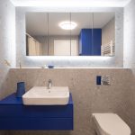 Modrá kúpeľňová skrinka so sivým veľkoformátovým obkladom na stenách