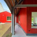 Červená fasáda nového objektu medzi domom a stodolou v Belgicku