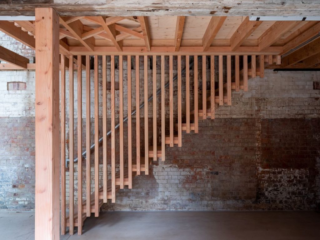 Drevené schodisko pripevnené o staré tehlové múry.