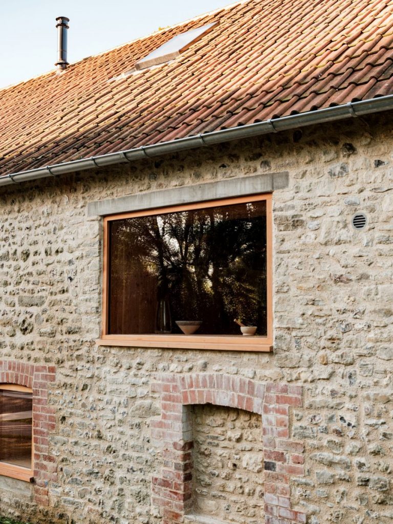 Jedno z okien s dreveným rámom v kamennej stene budovy.