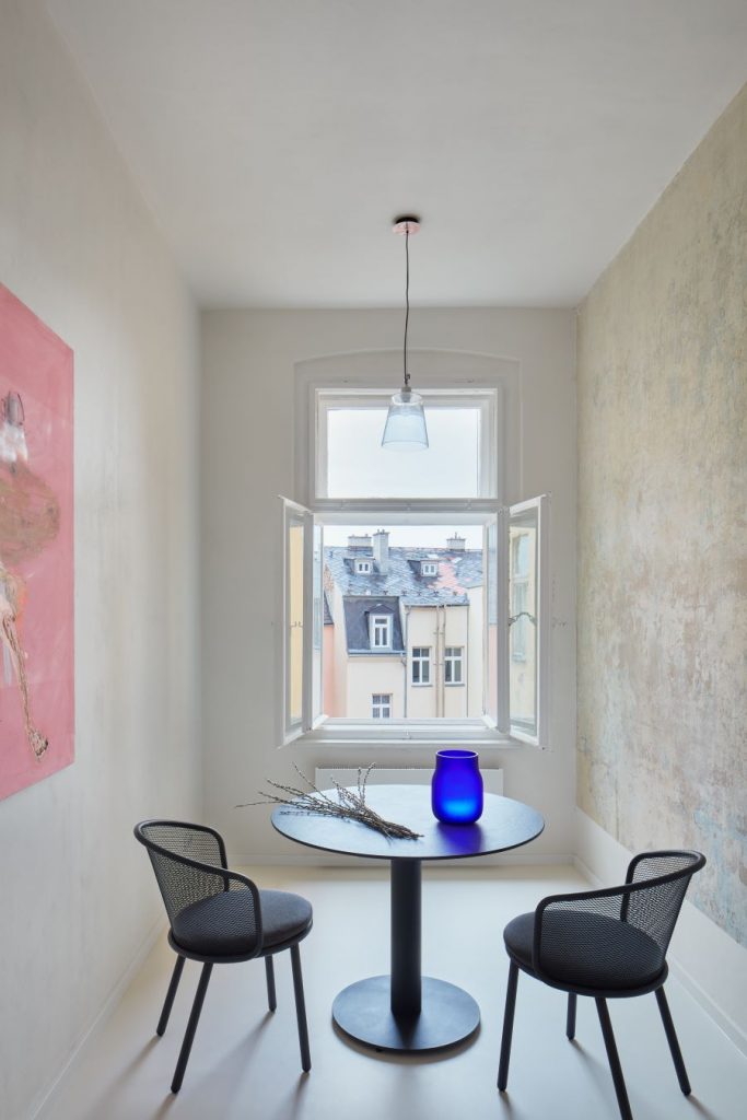 Miestnosť v byte v Karlových Varoch s okrúhlym stolom a dvoma stoličkami, otočenými k oknu.