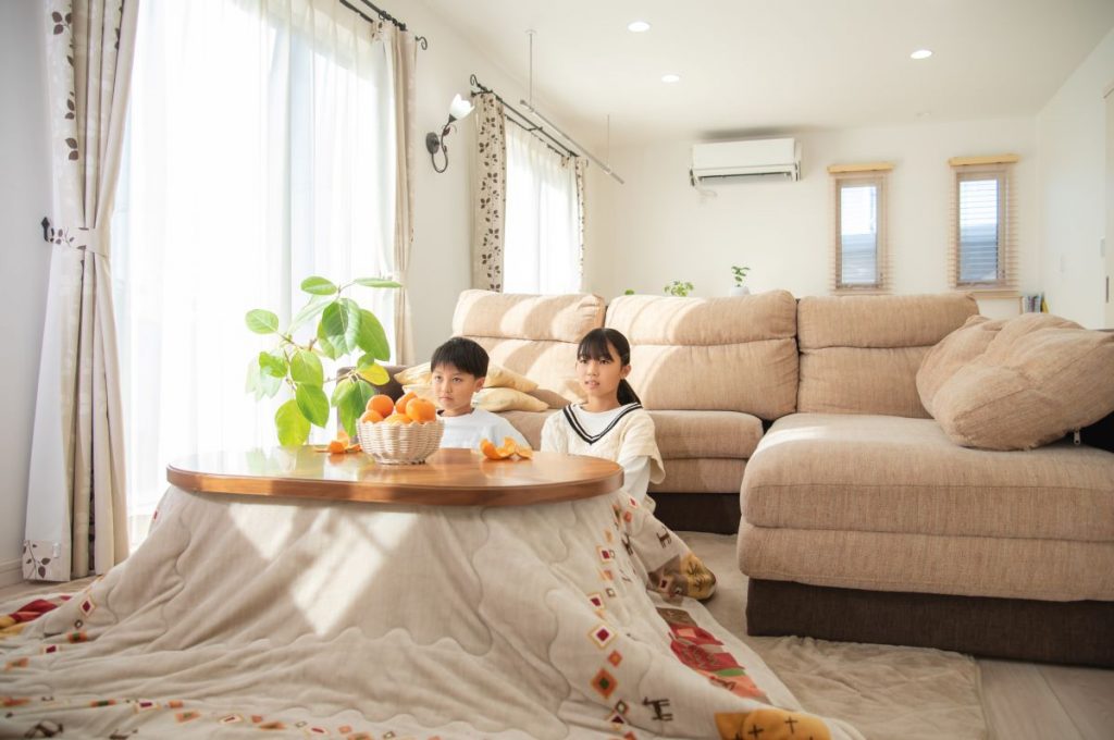 Chlapec a dievča sedia pri kotatsu v obývačke v Japonsku.