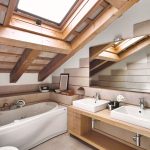 Podkrovná dreveno-biela kúpeľňa s toaletou, vaňou a dvoma umývadlami.