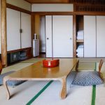 Interiér v japonskej domácnosti s nízkym dreveným stolíkom, vankúšmi na sedenie a oshiiru, skriňou na ukladanie matracov a vankúšov.