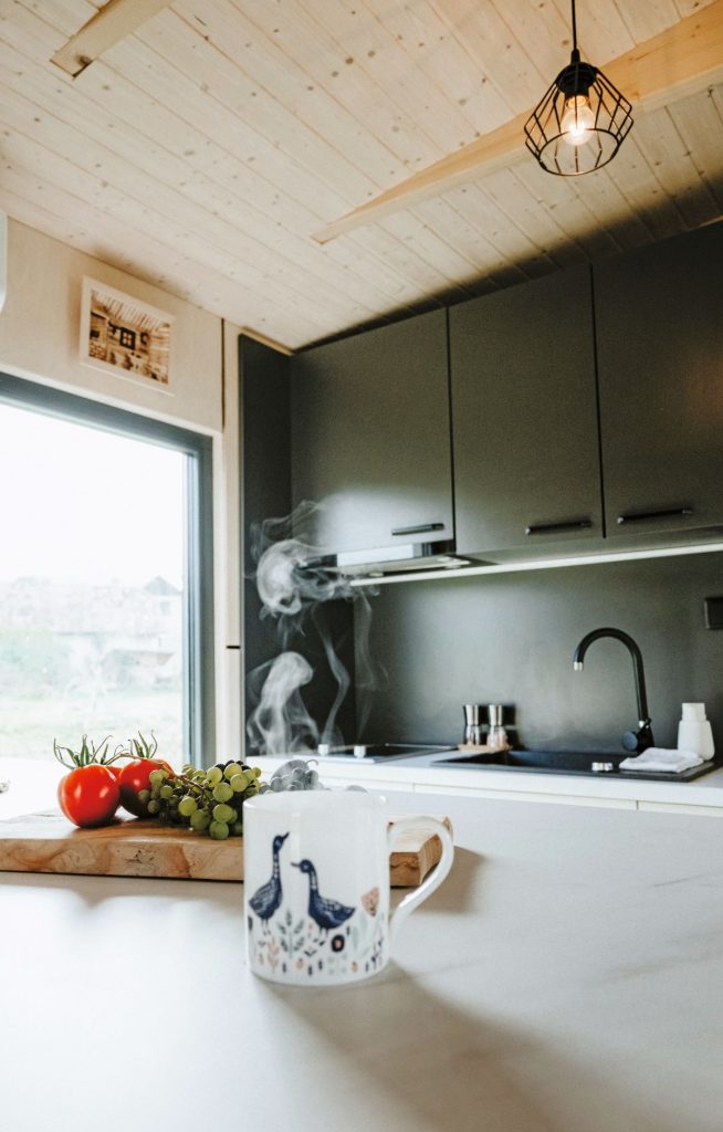 Kuchyňa v drevenom domčeku so smaragdovou linkou a svetlou pracovnou doskou.
