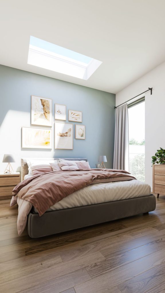 Manželská posteľ v spálni s modrou stenou a vysokým oknom.