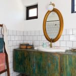 Kúpeľňa vo vidieckom štýle s oválnym zrkadlom a drevené skrinky, ladené do zeleno-modrá.
