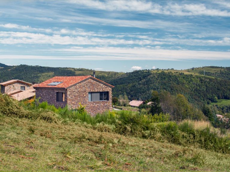 Výhľad z kopca na kamenný dom v obci Molló a okolité hory.